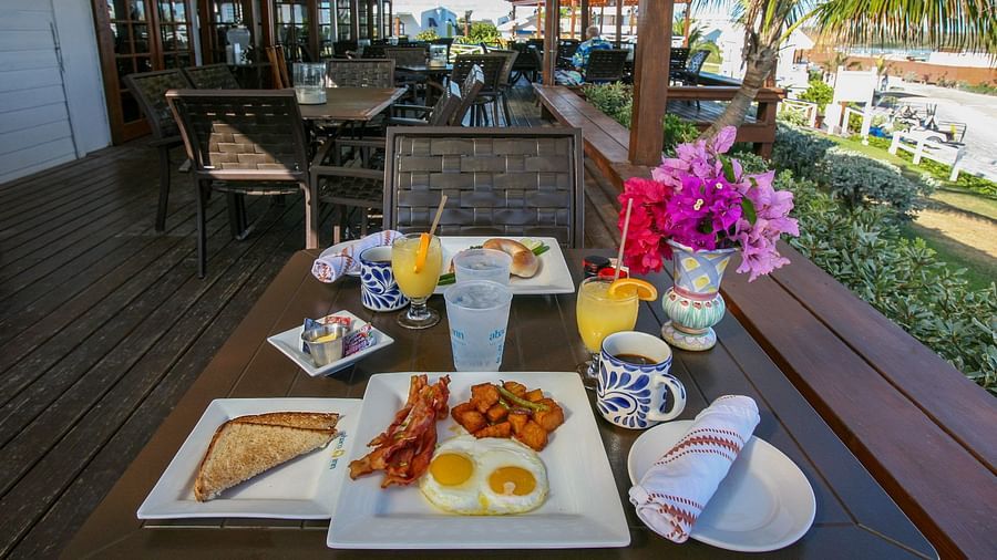 Table with breakfast plates under a shaded deck | Abaco Inn