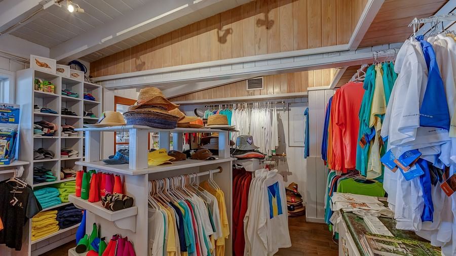 A well-organized apparel store displays colorful clothes on racks and shelves, with bright lighting and wooden flooring.
