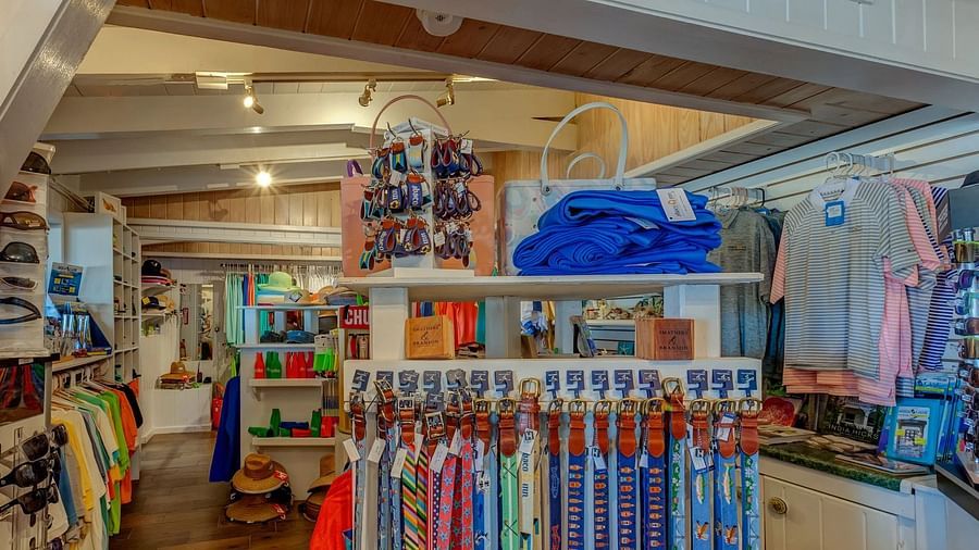 Inside a coastal retail store, racks are filled with clothes, bags, and accessories arranged neatly under warm ceiling lights.
