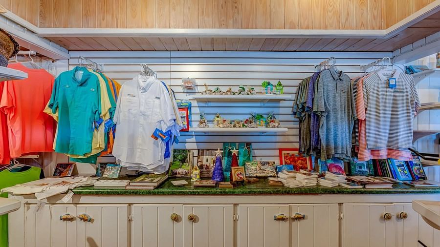Inside view of a boutique with brightly colored clothing, swimsuits, and beach accessories spread across the counters.
