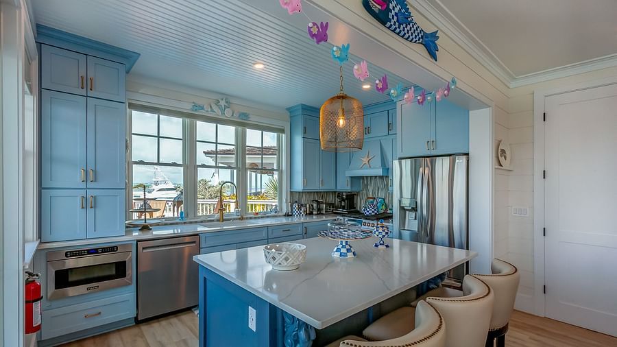 Bright, airy , white and blue coloured theme kitchen with a  table, chairs and windows that overlook the sea at Abaco Inn.