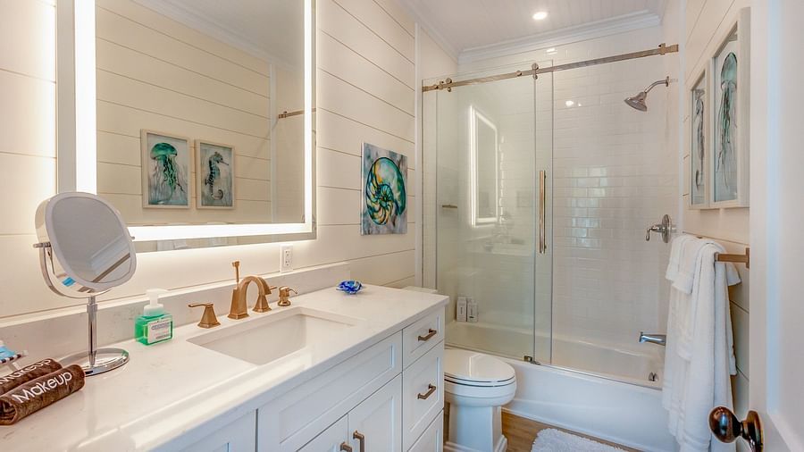 a well lit bathroom with drawers, a huge mirror, a commode and a walk in shower  at Abaco Inn.