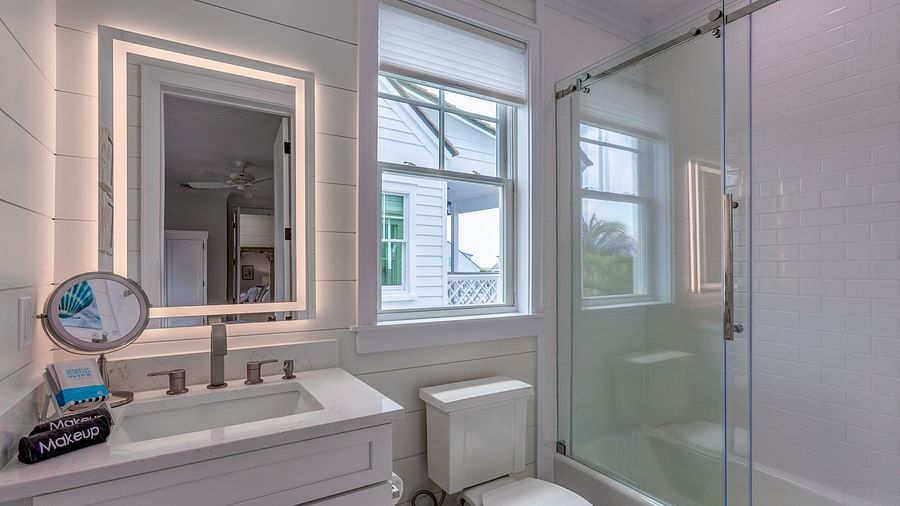 a bathroom with a sink, a huge mirror, a commode, a walk in shower and a window at Abaco Inn.