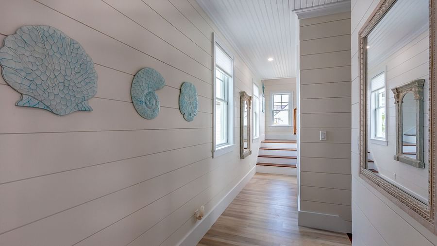 corridor at Abaco Inn with wooden floor and white walls with mirror, seashell decors  and windows.