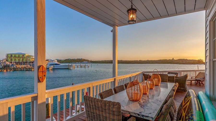 a balcony with a dining area featuring  Marble top dining table, chairs, and a sea view at  Abaco Inn.