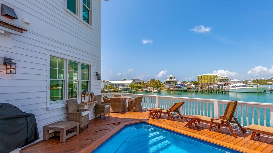 a swimming pool on a wooden dock and chairs with a sea view at Abaco Inn.