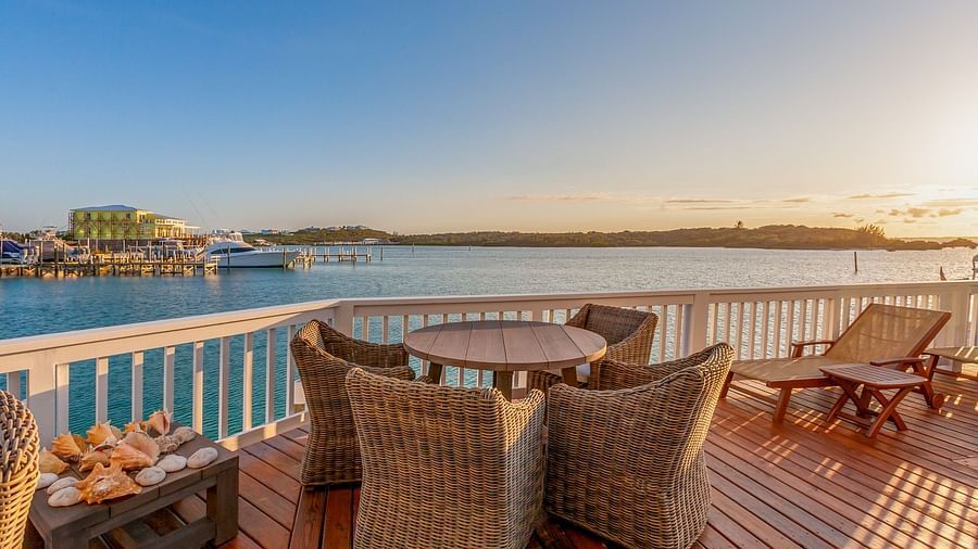 outdoor sitting area with wooden floor, tables and chairs and a view of the sea at Abaco Inn.