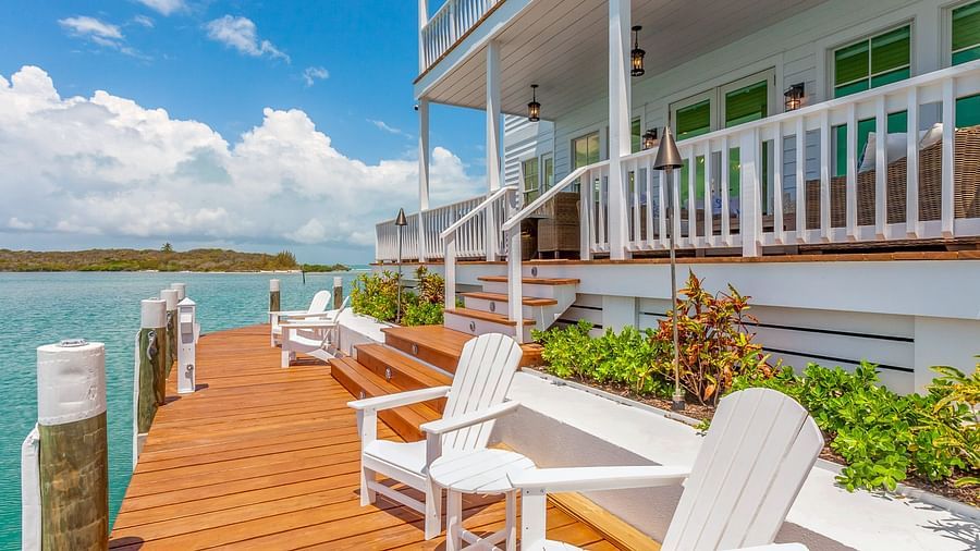 facade of the Abaco Inn with chairs on the dock and a view of the sea.