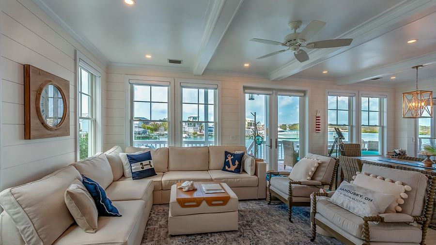 a sitting area with sofas and a table, a ceiling fan, wall decors, and glass doors and windows with a sea view at Abaco Inn.