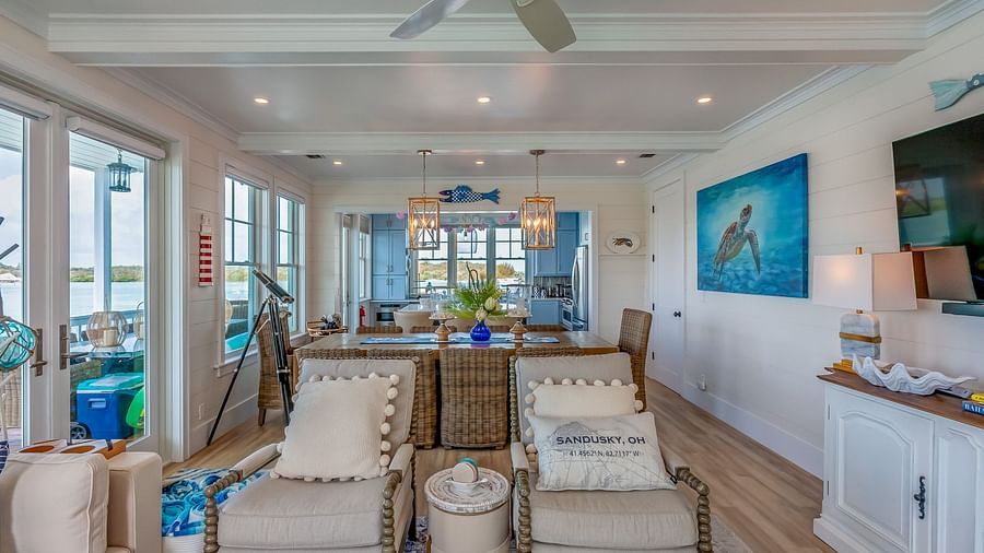 A sitting area with sofas and TV, A wooden dining table with wooden chairs, a telescope and ceiling fan at Abaco Inn.