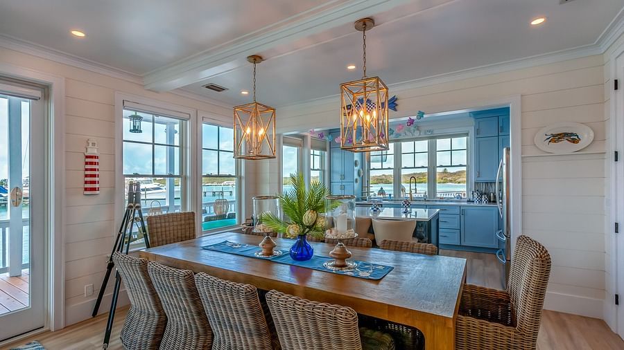 well lit kitchen with a dining area featuring wooden table and chairs, and windows overlooking the sea at Abaco  Inn.