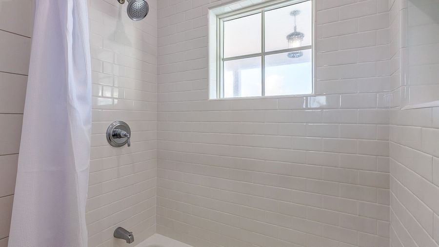 a bathroom of Abaco inn with curtained bathtub and shower, and a small window above.