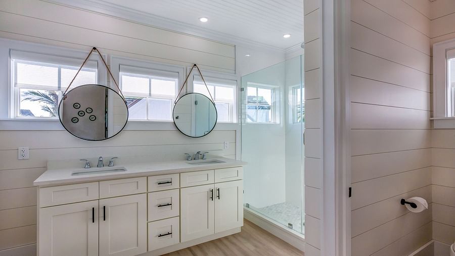 bathroom with cupboards, two sinks and two circular hanging mirrors at Abaco Inn.