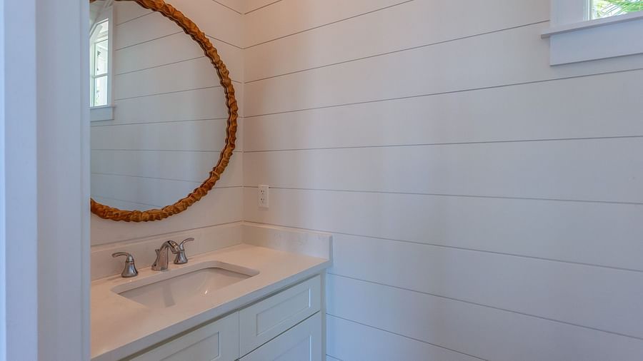 Bathroom with a sink , cupboard and a circular mirror at Abaco Inn.