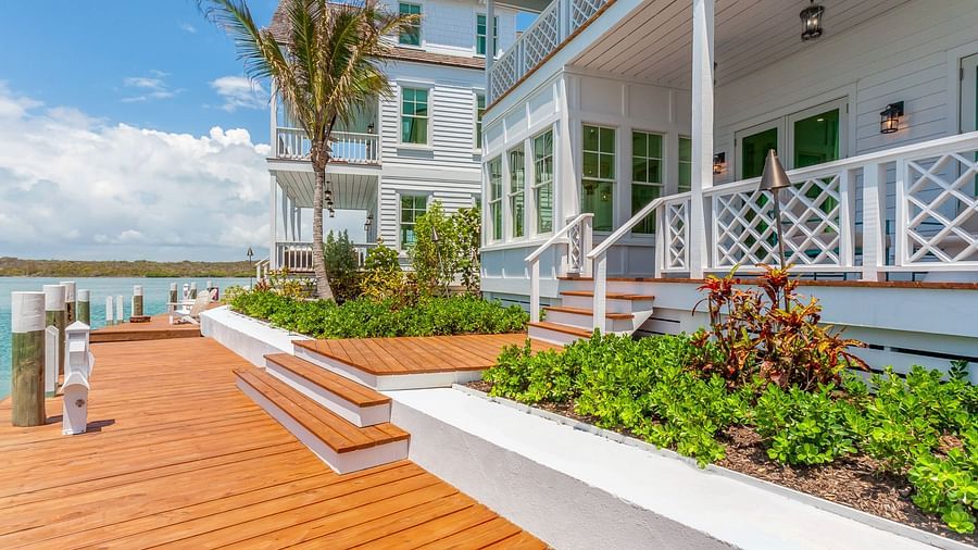 Facade of Abaco Inn with wooden dock, potted plants and a palm tree.