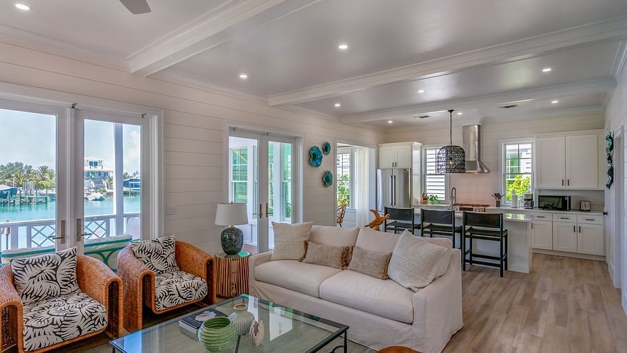 a sitting area with sofas, a glass table, chairs, wall decors and windows overlooking greenery at Abaco Inn.