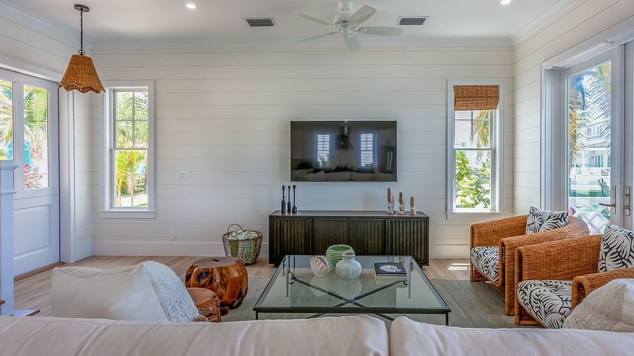 Sitting area of Abaco Inn with sofas, Glass table, TV unit, and windows overlooking greenery.