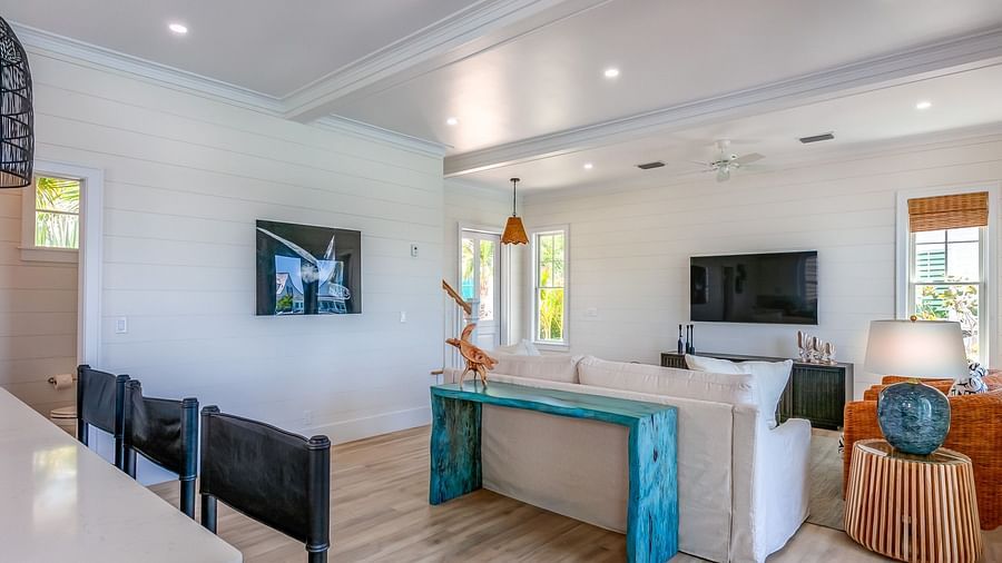 a sitting area with a sofa, TV, table, chairs, wall decors and windows overlooking greenery at Abaco Inn.