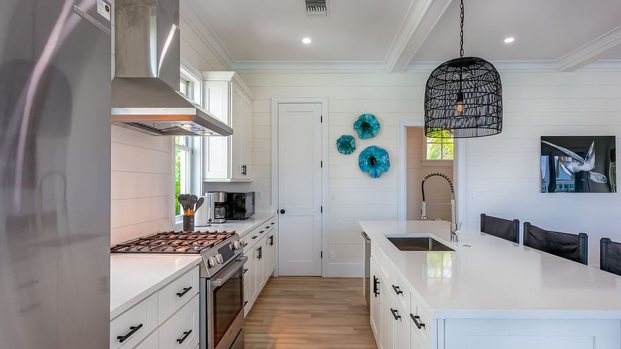 well lit Spacious kitchen with marble top table, chairs, cupboards, fridge, oven and a chimney at Abaco Inn.