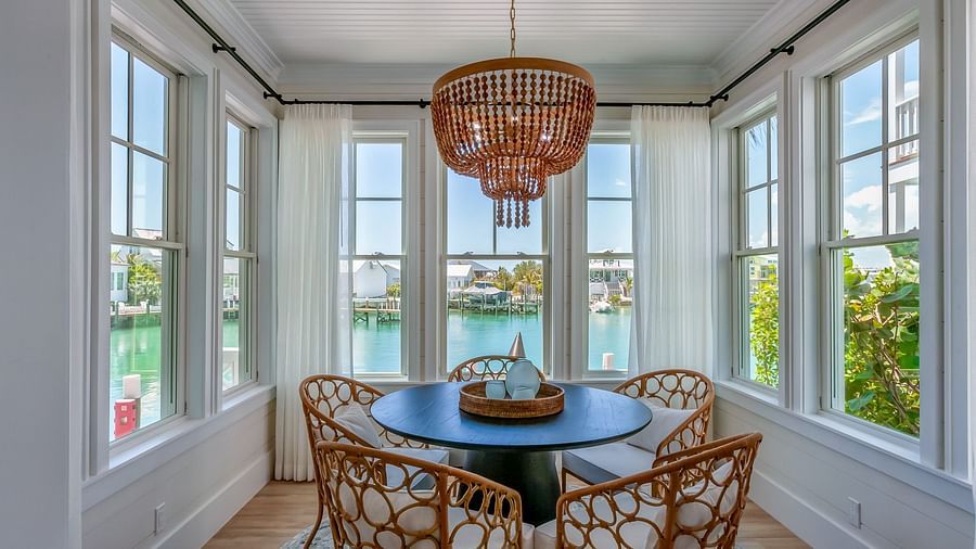 sitting area of Abaco Inn with a table and wooden chairs surrounding it, and windows overlooking the sea.