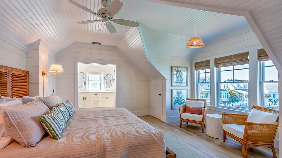 a bedroom at Abaco Inn with a huge bed, wooden floor, chairs, table, ceiling fan and windows overlooking the sea view.