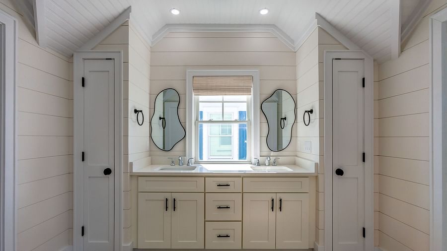a bathroom with a sink, cupboards , mirrors and a window at Abaco Inn.