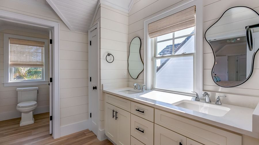 A bathroom with a commode, cupboards, sink, mirrors and a window at Abaco Inn .