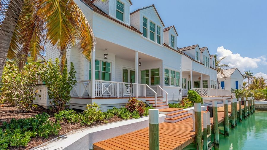 Facade of Abaco Inn with wooden dock, potted plants and a palm tree.