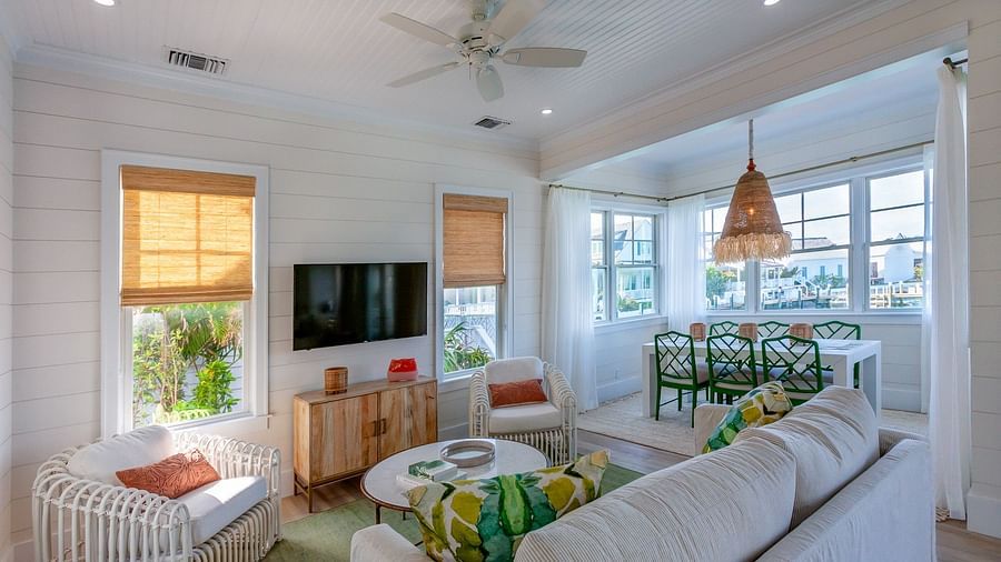 Sitting area at Abaco Inn with sofas, Table, Chairs, TV and windows overlooking  greenery.