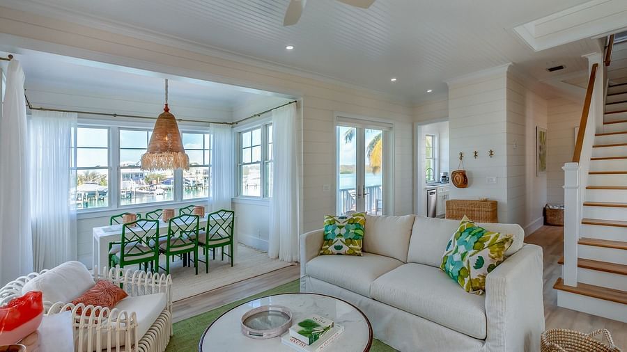 Sitting area at Abaco Inn with sofas, Table, Chairs, and windows overlooking  greenery.