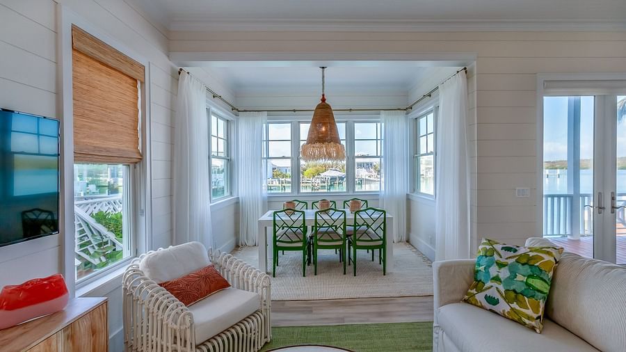 Sitting area at Abaco Inn with sofa, chairs, table, TV and windows overlooking the sea.