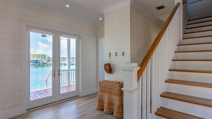 Stairways of Abaco Inn with wooden floor and sliding glass door leading to a dock with sea view.