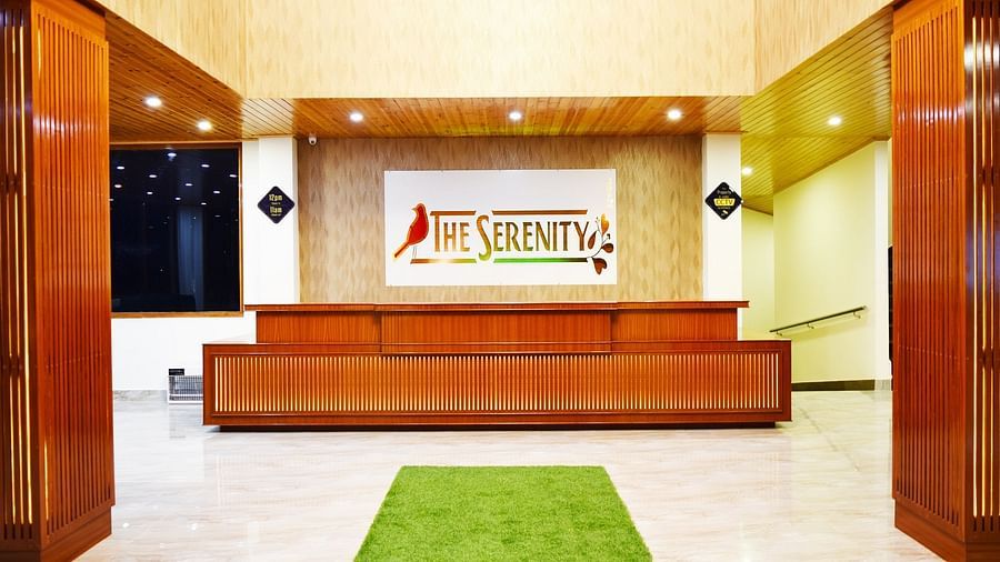 Image of the reception area of a hotel with a wooden counter and green carpet  | DLS Serenity Resort and Spa