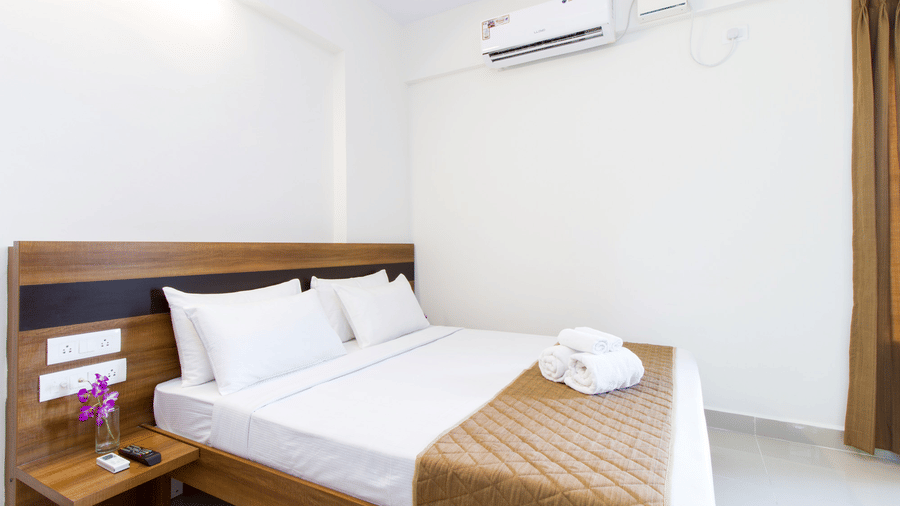 Neatly made double bed with fresh linens at Sanctum Suites Whitefield Bangalore, showcasing rooms near Kadugodi.