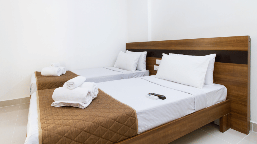 Hotel room with a double bed, crisp white linen, and a neatly arranged towel set at Sanctum Suites Whitefield, Bangalore.
