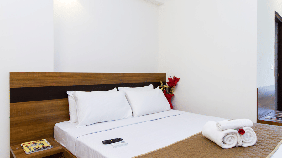 Hotel room with a double bed, crisp white linen, and neatly folded towels at Sanctum Suites Whitefield, Bangalore.
