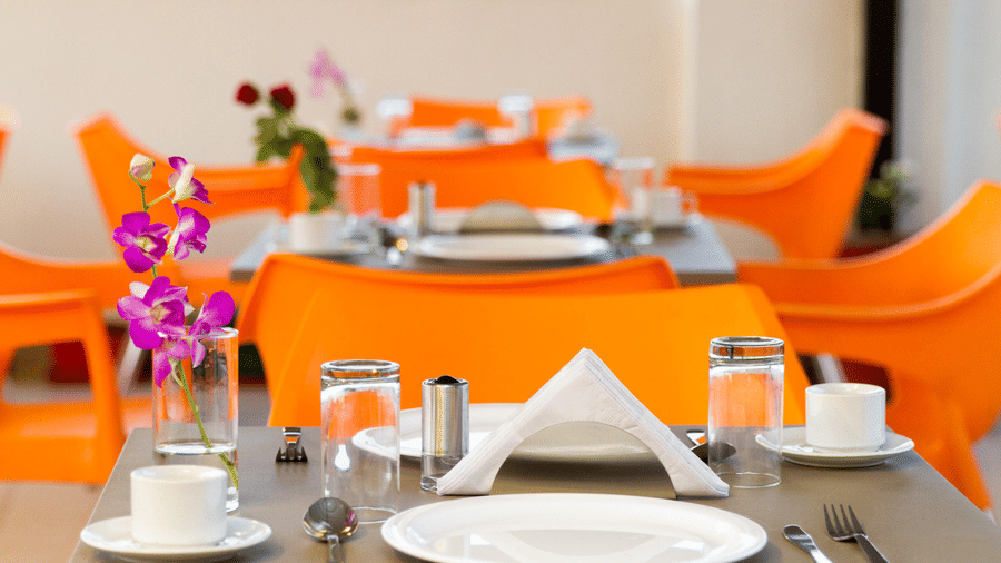 Close-up of a rooftop table setting with glassware, white linen, and orchid flowers at Sanctum Suites Whitefield, Bangalore.