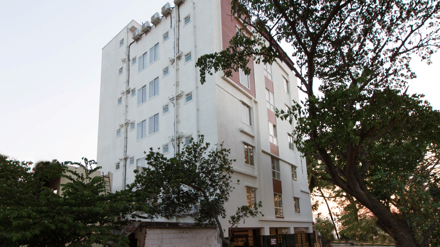 Exterior view of Sanctum Suites, a modern hotel in Whitefield Bangalore surrounded by lush trees.