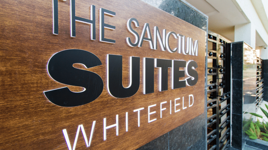 Daytime view of The Sanctum Suites Whitefield wooden brand signage at Sanctum Suites Whitefield, Bangalore.