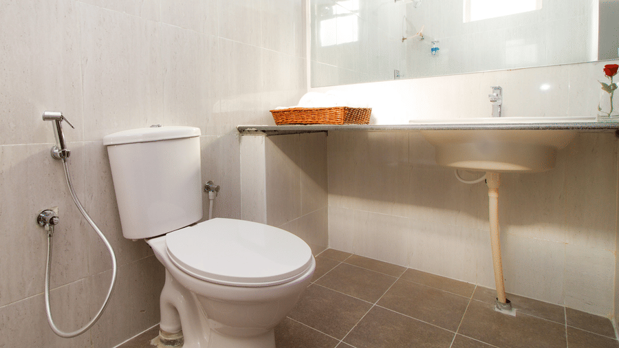 Modern bathroom with a shower, a toilet, and premium fittings at Sanctum Suites Whitefield, Bangalore.