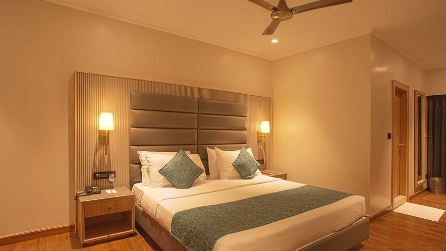 a double bed with side lamps and tables inside Pool view room - The Cindrella Hotel, Siliguri