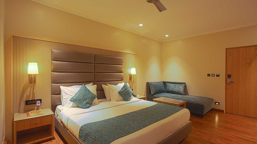 a double bed with side table and lamps inside Pool view room - The Cindrella Hotel, Siliguri