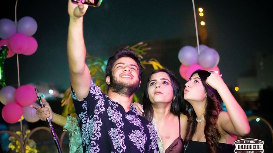 An image of a group of three people clicking a selfie on a party at Themis Barbecue House, NSP Pitampura