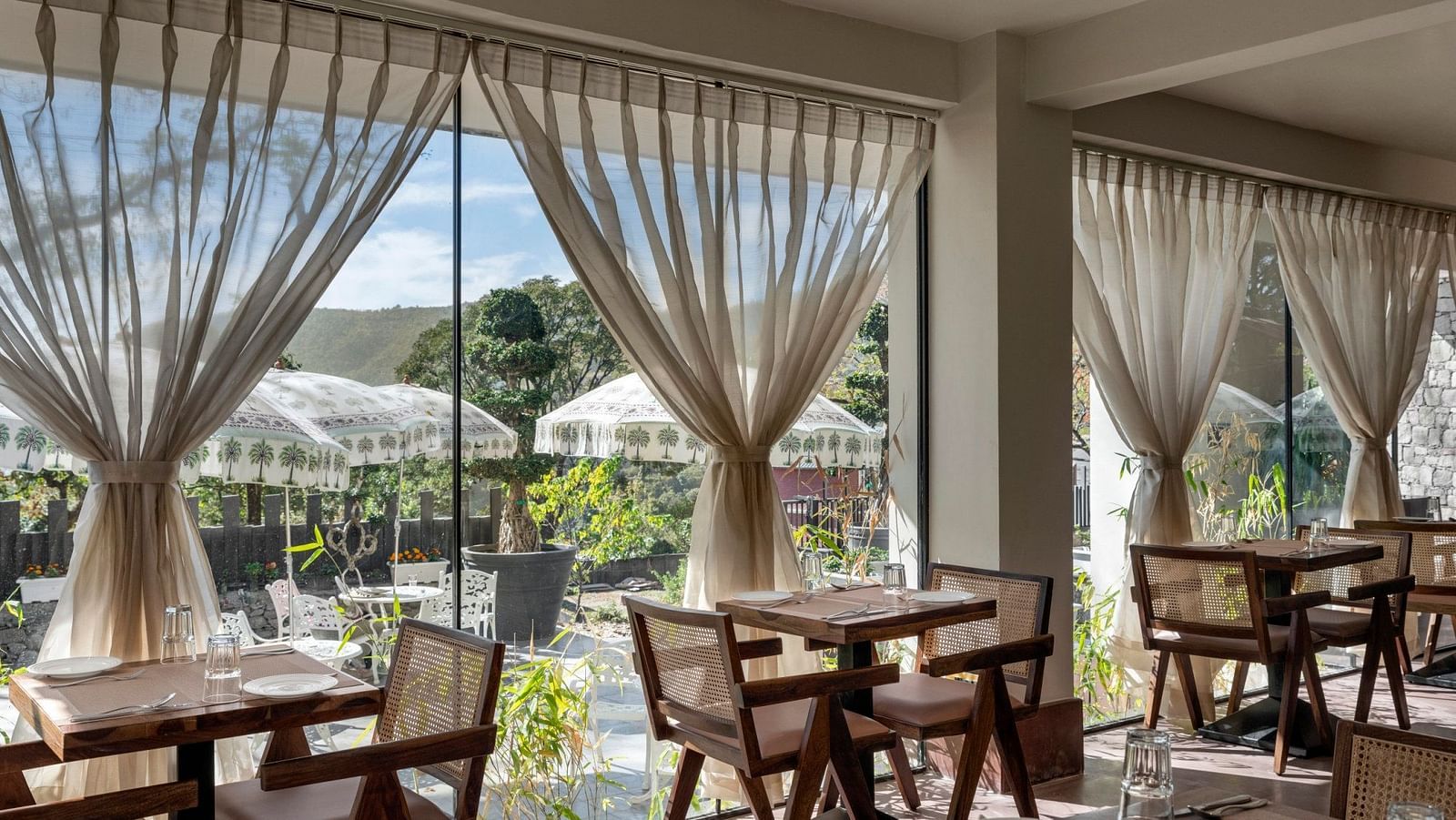 An inside view of a restaurant with chairs placed beside a glass window - The Samai, Bhimtal