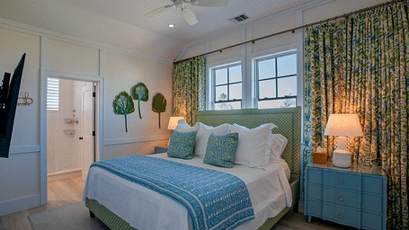 Bedroom with green floral curtains, a blue dresser, and white bedding | Abaco Inn