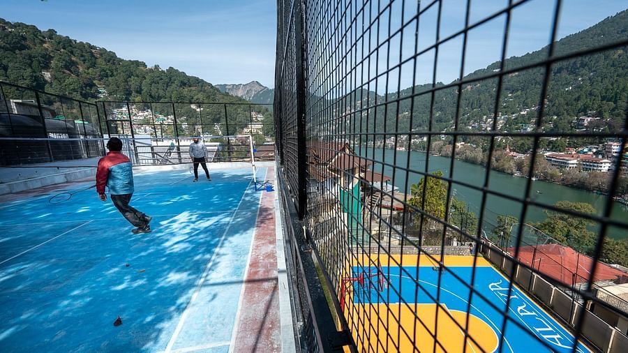Two men playing badminton with a river view beside them at Himalaya Hotel, Nainital