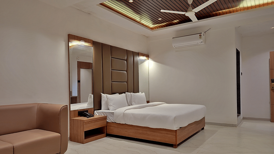 Spacious bedroom with a double bed, padded headboard, seating area, and ceiling fan