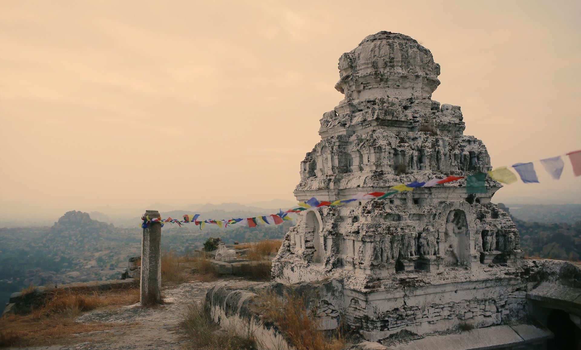 Ancient Hampi temple ruins with colorful prayer flags.