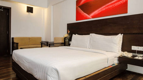A bedroom with a king size bed, wall panel, lighting, side tables, chair, and sofa arranged indoors at Springs Hotel & Spa, J.C. Road.