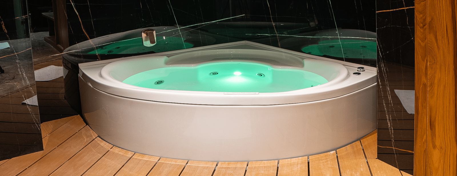 A jacuzzi with bubbling water placed in a wooden deck enclosure at Infiniti Hotel, Indore.
